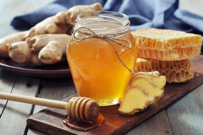 Honey in jar with fresh ginger on vintage wooden background